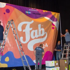 A group of men installing a large banner on a stage.