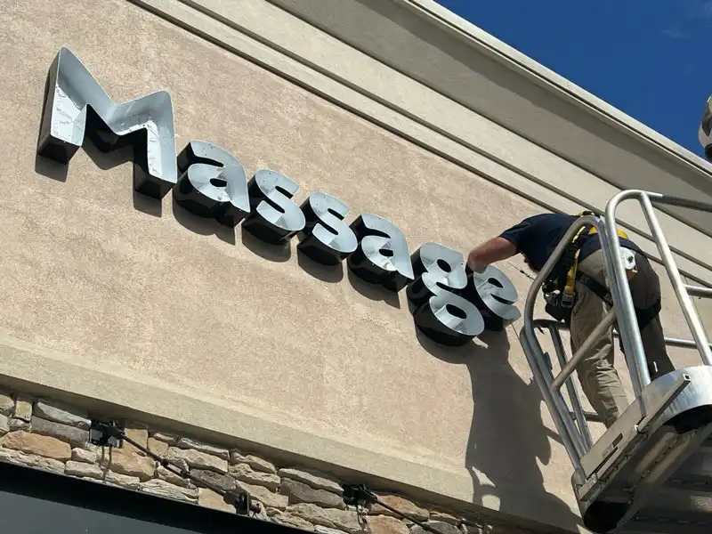 Illuminated Dimensional Letters being installed on a building by a man in a bucket truck.