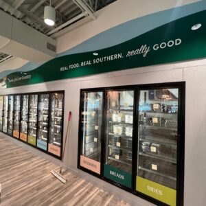 Store sign with pelican logo and 'Taste of the Low Country' text above freezer section.